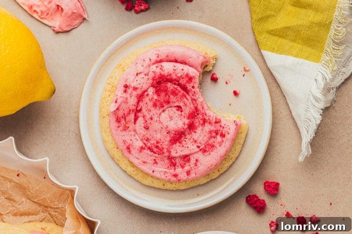 A single beautifully frosted lemon sugar cookie presented on a clean white plate.