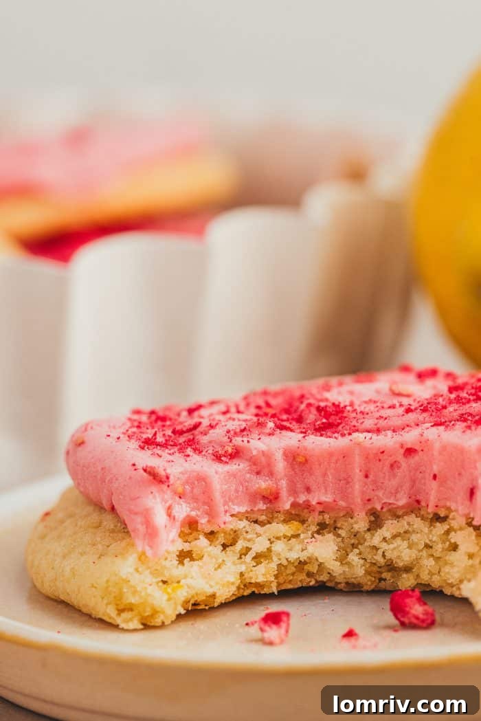 A solitary lemon sugar cookie, beautifully frosted, presented on a white plate with subtle lighting.