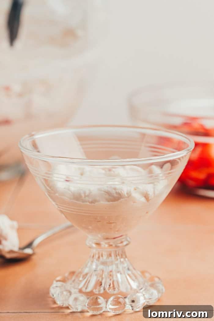 A scoop of strawberry fool in a glass serving dish.
