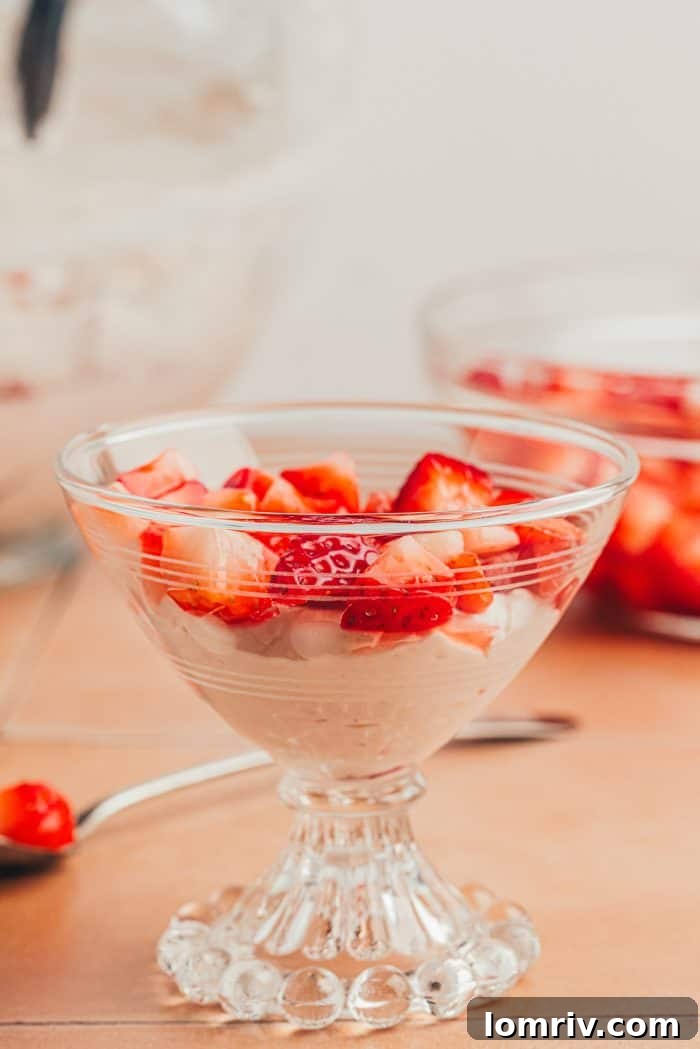 A layer of strawberries added to the strawberry fool in a glass serving dish.