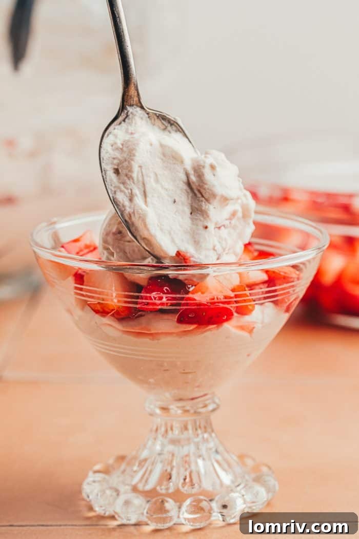 A layer of strawberry fool over fresh strawberries in a glass serving dish.