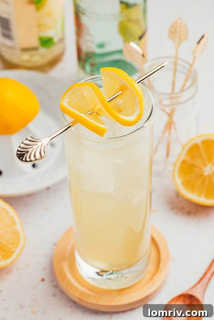 A single tall glass of lemon elderflower mocktail with a lemon slice garnish, invitingly cool.