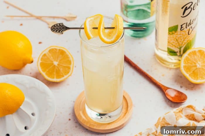 A close-up of a lemon elderflower mocktail glass, highlighting the garnishes and refreshing bubbles.