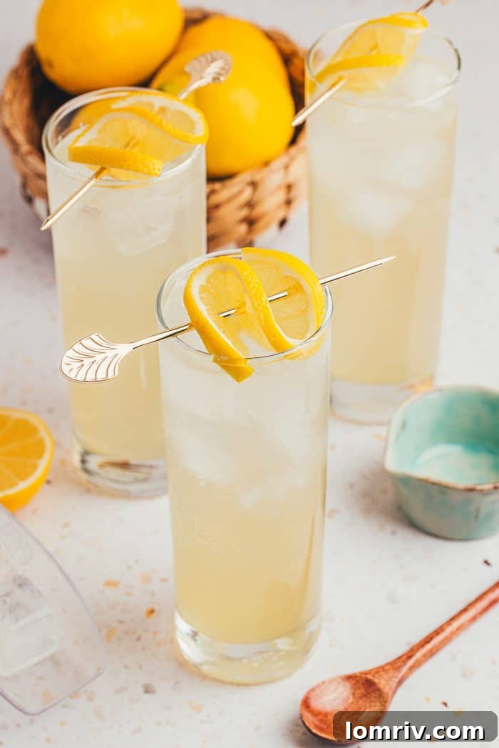 Three tall glasses filled with vibrant lemon elderflower mocktail, ready for serving.