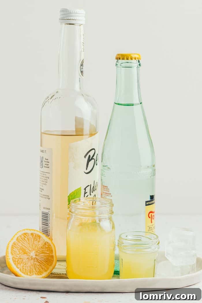 All the essential ingredients neatly laid out for making the lemon elderflower mocktail: cordial, lemon, lime, sparkling water, and ice.