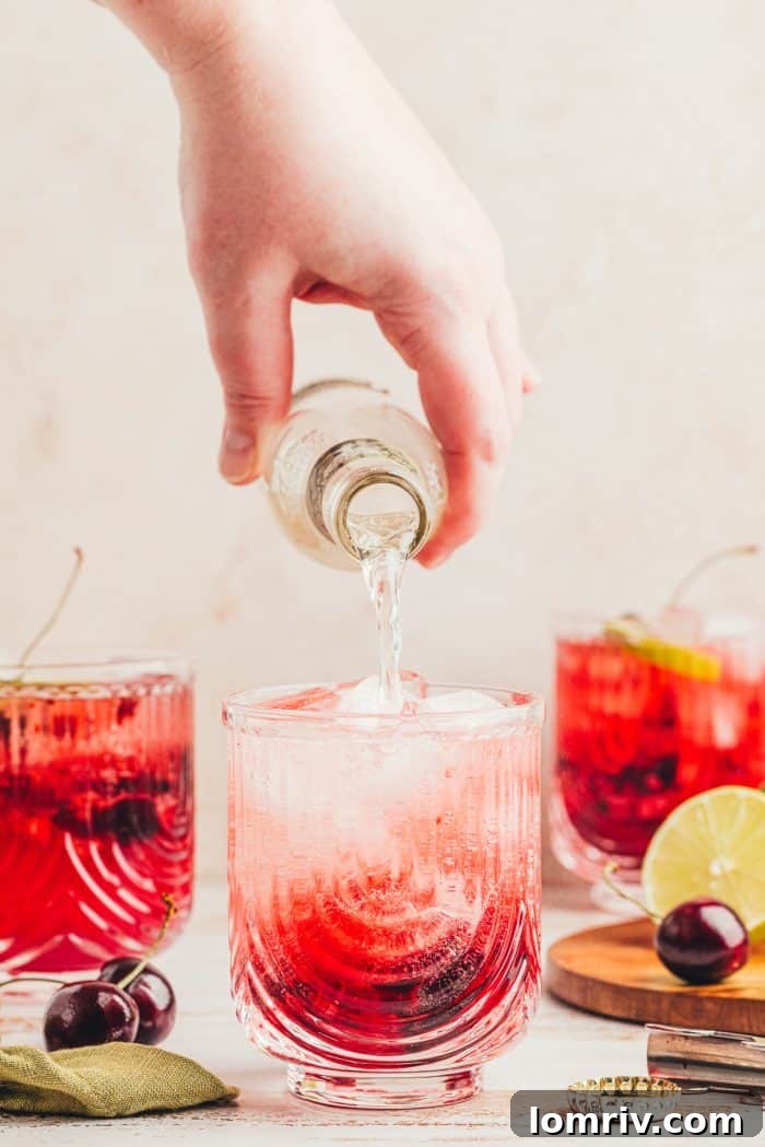 Three virgin cherry Moscow mules in glasses with ginger beer being poured into one.