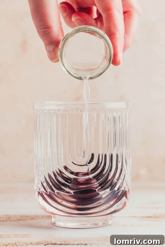 A glass with lime juice being poured into it.