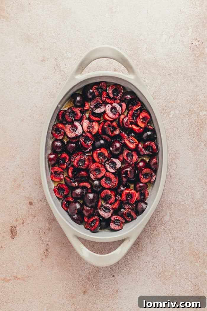 A white oval dish with sliced cherries in it.