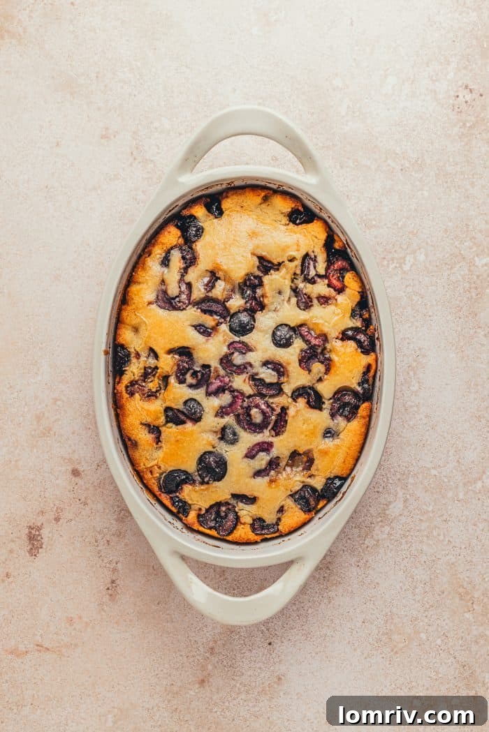 A white oval dish with baked cherry cobbler in it.