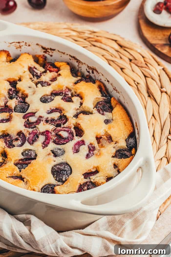 A white oval dish with baked cherry cobbler in it.