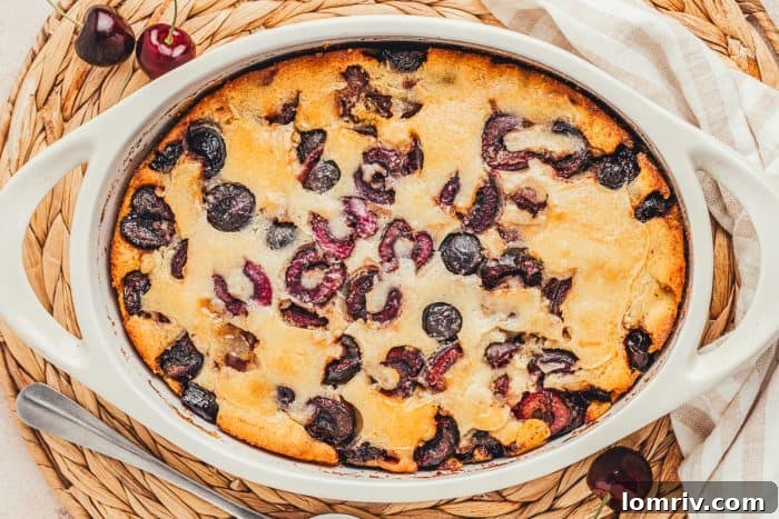 A white oval dish with baked cherry cobbler in it.