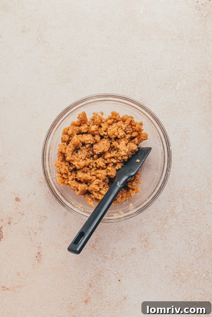 The golden crumb mixture, perfectly textured, resting in a glass bowl before being added to the cake.