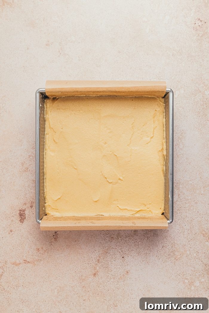 The smooth cake batter evenly spread into the prepared square baking pan.