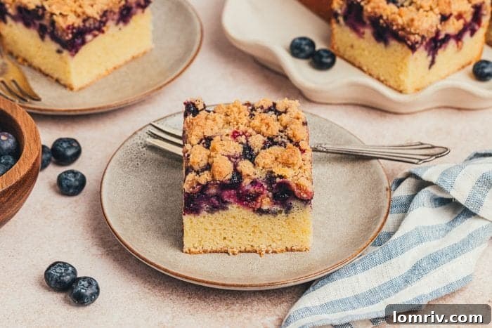 Three perfectly cut slices of blueberry crumb cake on individual small plates.