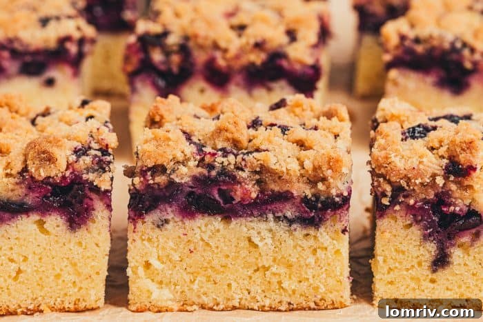 Six perfectly baked slices of blueberry crumb cake on a wooden board.
