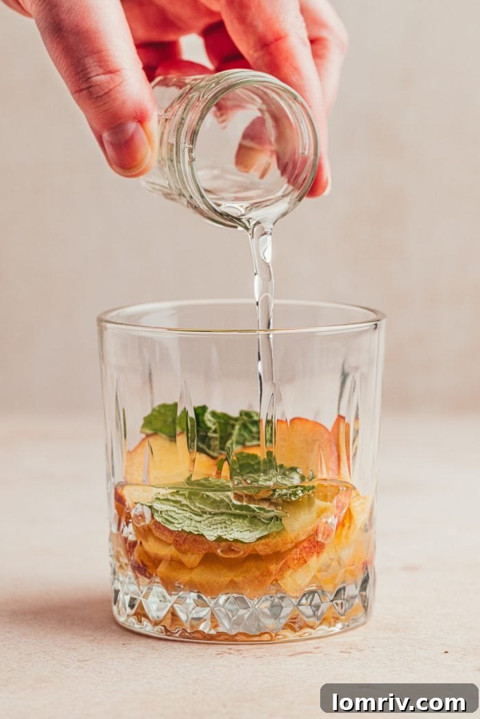 Peaches in a glass with simple syrup being poured in it.