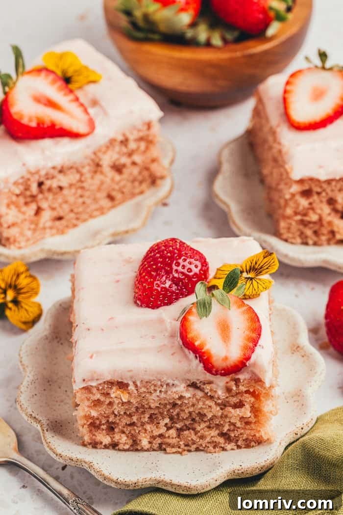 Delightful slices of strawberry sheet cake presented on plates, garnished with fresh strawberries