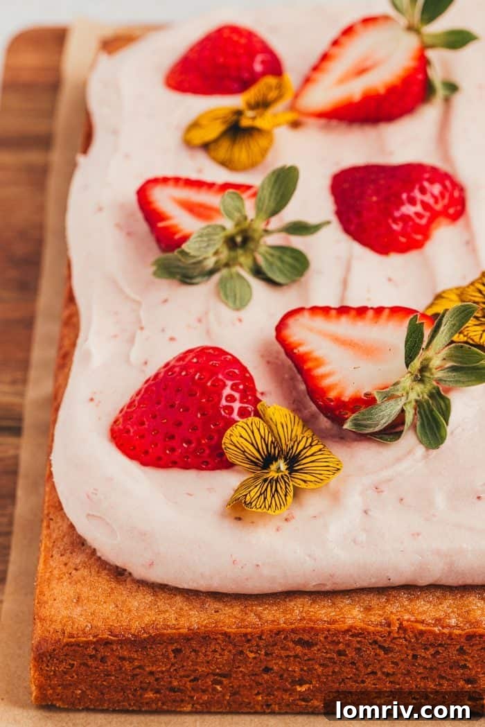 Close-up of decorative elements for a strawberry sheet cake, featuring fresh berries and delicate edible flowers