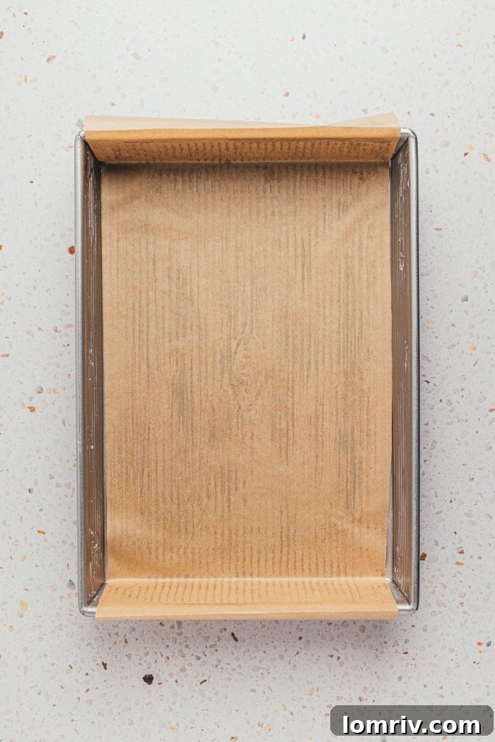 A baking pan meticulously prepped with parchment paper and grease, ready for the cake batter