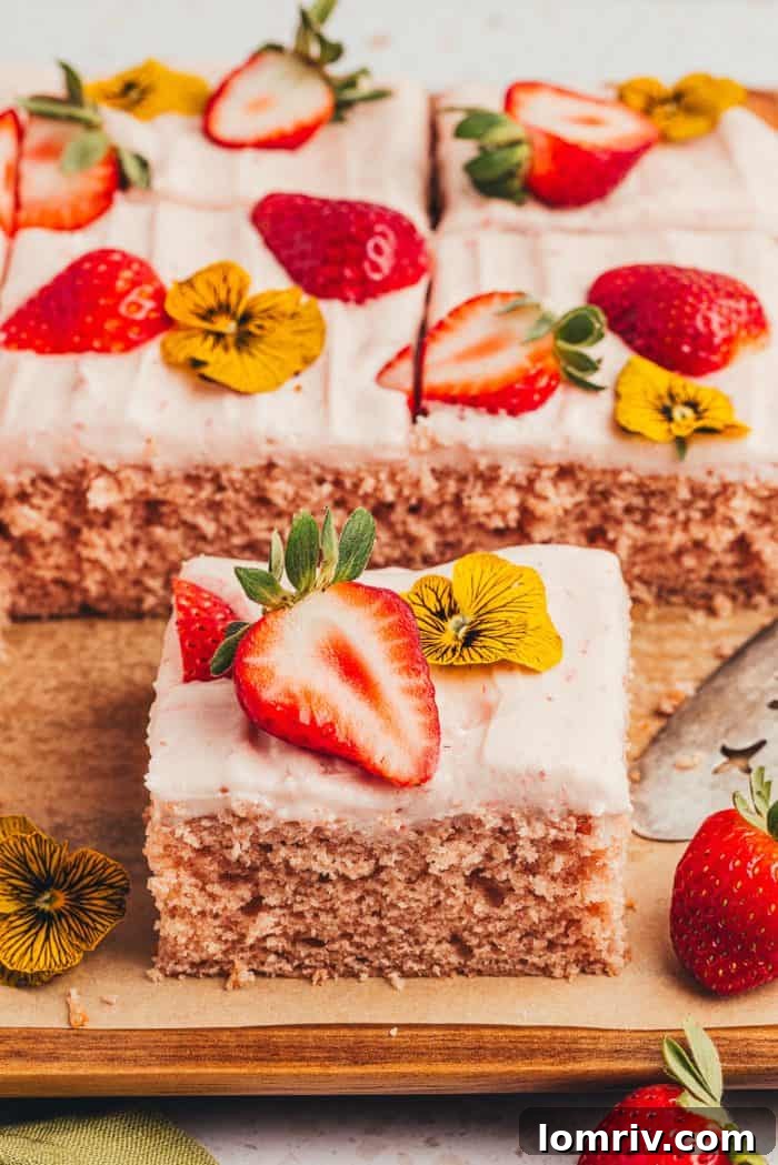 A beautifully baked strawberry sheet cake, sliced on a rustic wooden board, ready for serving