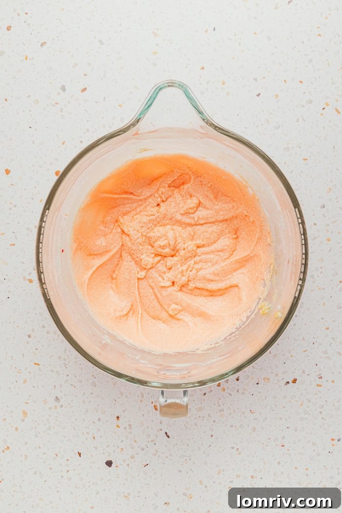 The vibrant pink batter for strawberry sheet cake in a glass mixing bowl, ready for baking