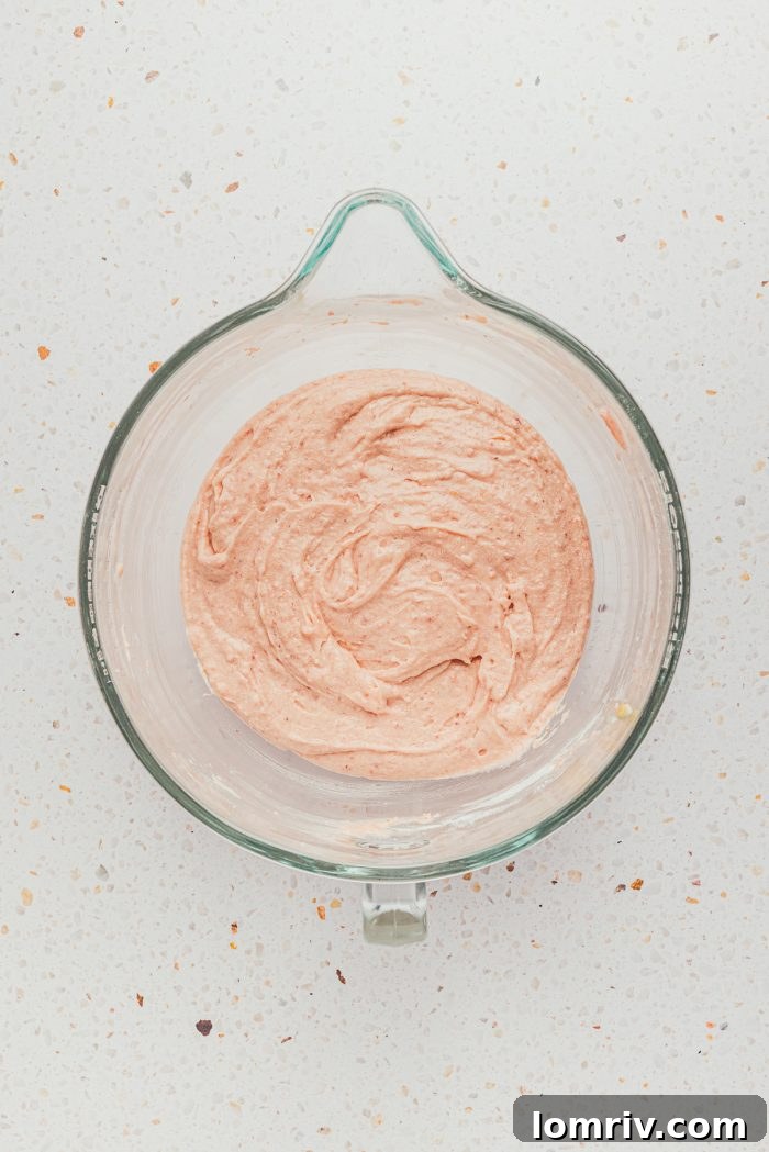 Creamy strawberry frosting in a mixing bowl, perfectly whipped and ready to be spread