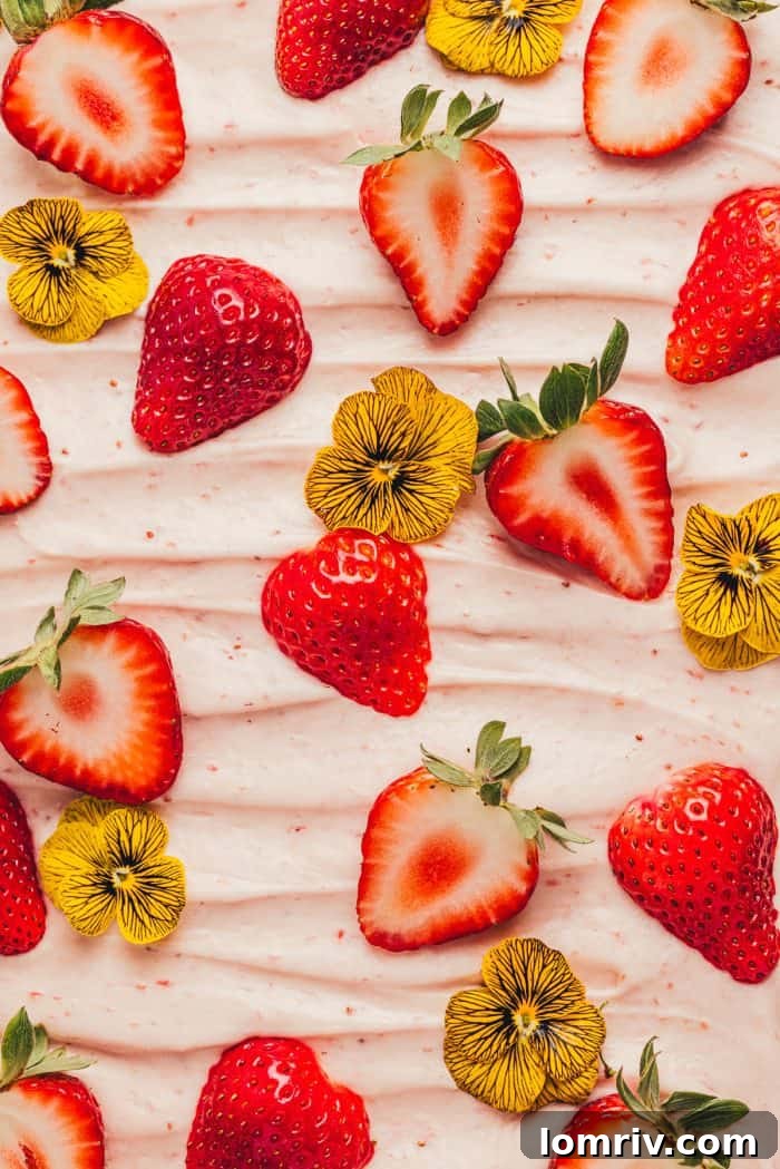 Close-up of decorative elements for a strawberry sheet cake, showcasing fresh berries and edible flowers