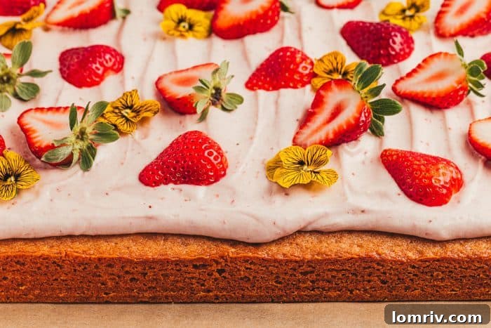 An intimate view of a decorated strawberry sheet cake on a wooden cutting board, emphasizing its charming presentation