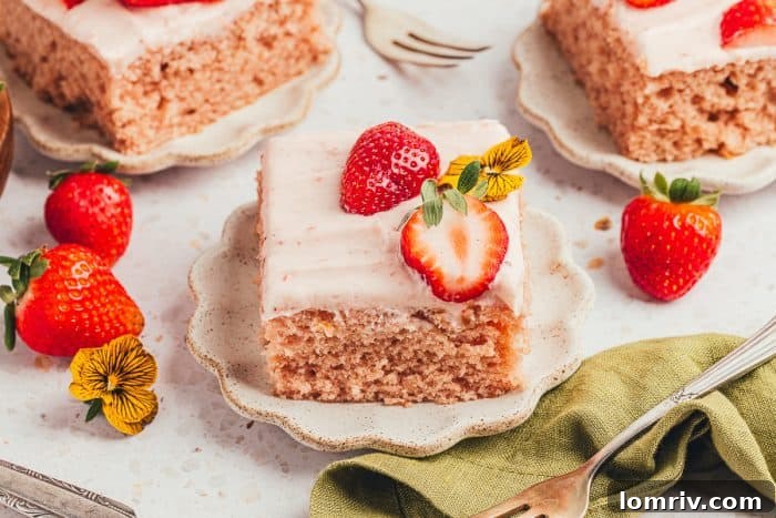 Three perfectly portioned slices of strawberry sheet cake on elegant plates, surrounded by fresh strawberries, ready for a delightful dessert experience