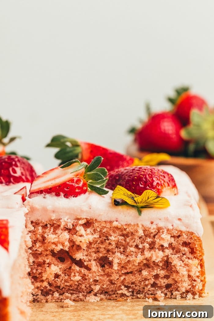 A perfectly sliced piece of homemade strawberry sheet cake, revealing its moist crumb and creamy frosting