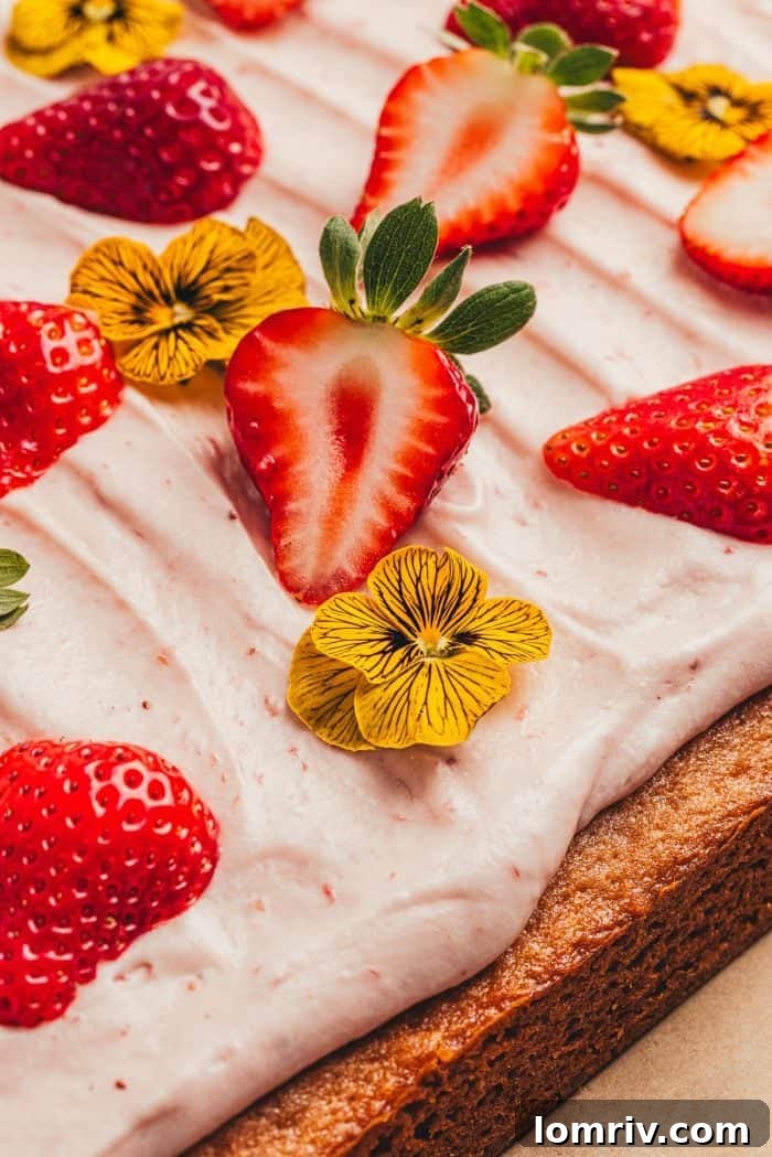 Close-up of decorative elements for a strawberry sheet cake, including fresh berries and edible flowers
