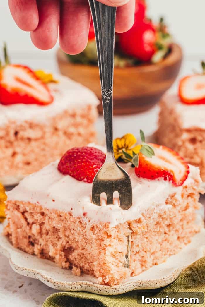 Three slices of delectable strawberry sheet cake, beautifully arranged with fresh strawberries on the side