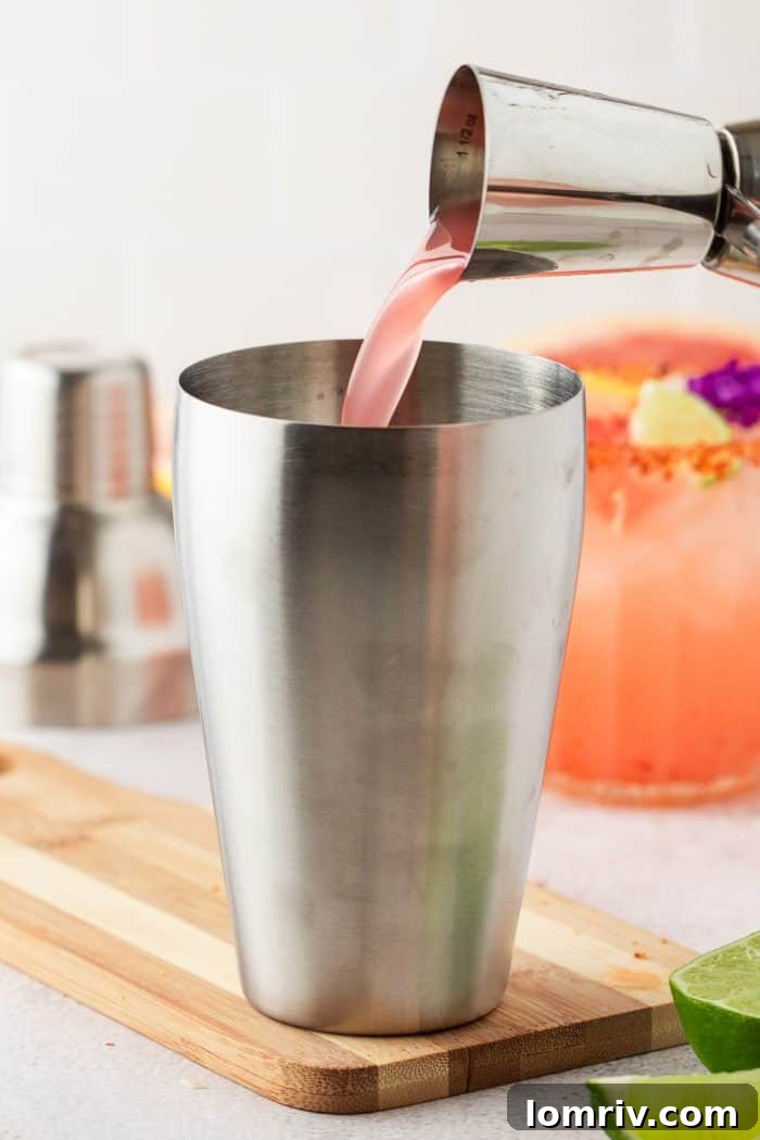 A cocktail shaker being filled with the various liquid ingredients for the Guava Paloma, prior to shaking.