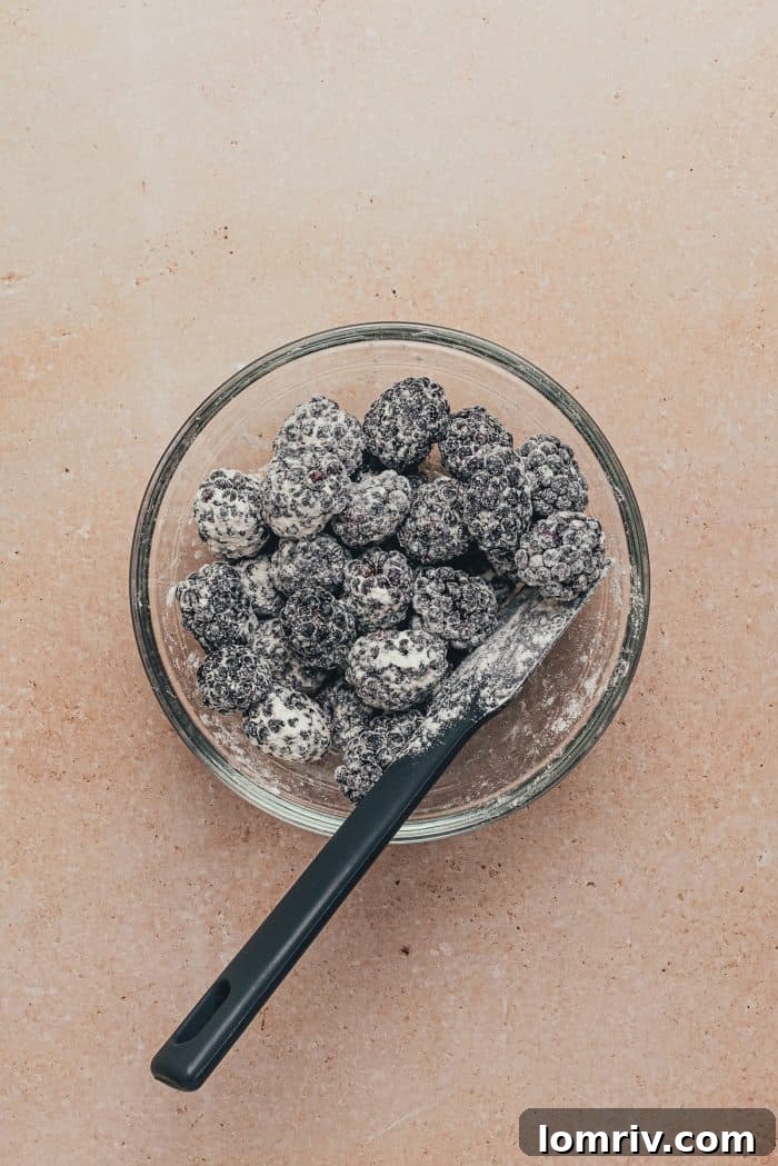 Fresh blackberries lightly tossed in flour in a clear glass bowl.