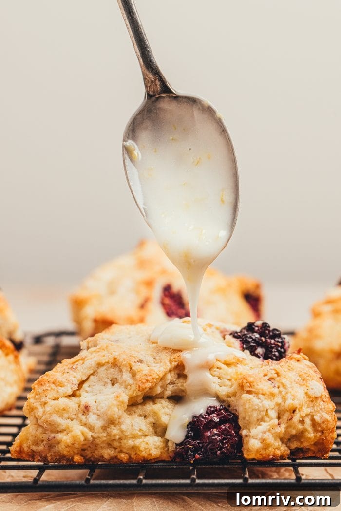 A single glazed blackberry scone with lemon glaze dripping down its side.