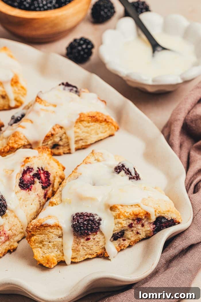 Beautifully glazed blackberry scones presented on a white platter.