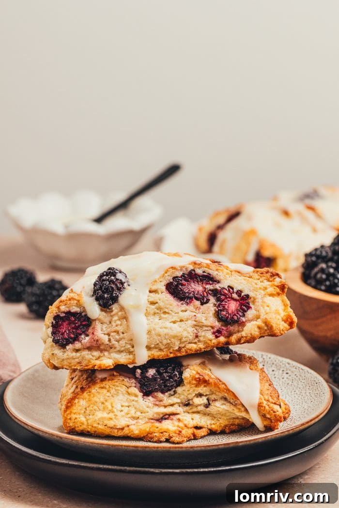 Two blackberry buttermilk scones stacked on a white plate, showcasing their inviting texture.