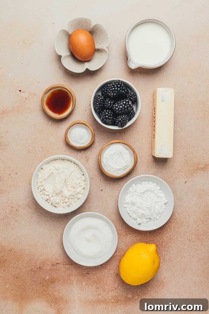 Various ingredients for scones, including flour, sugar, butter, and blackberries, arranged in bowls.