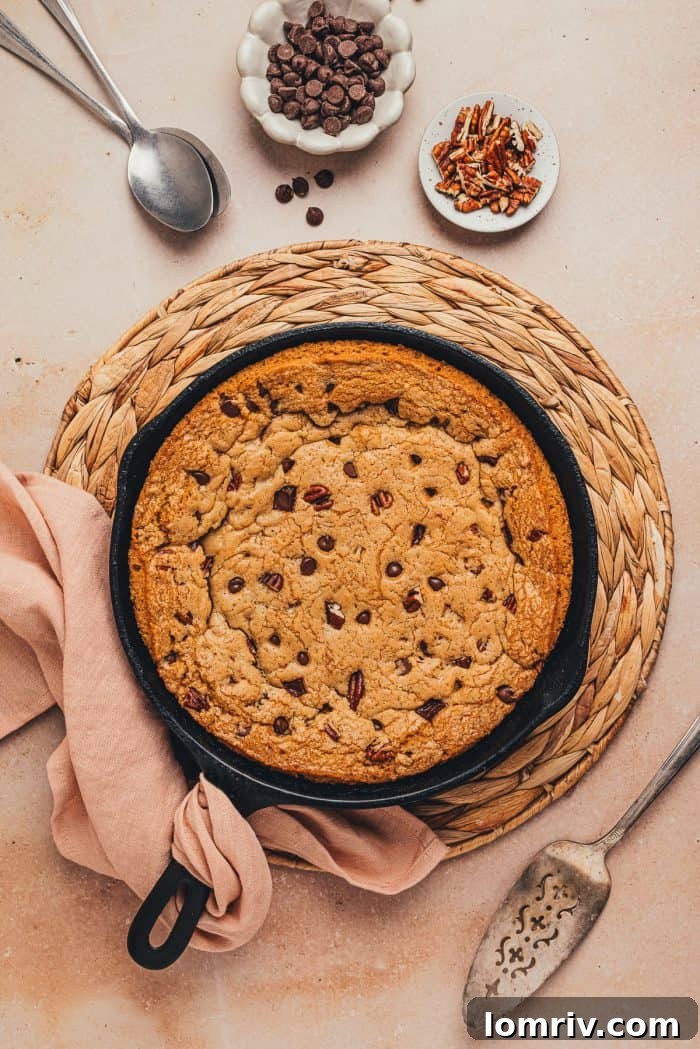 A baked chocolate chip cookie skillet on a placemat with a napkin.
