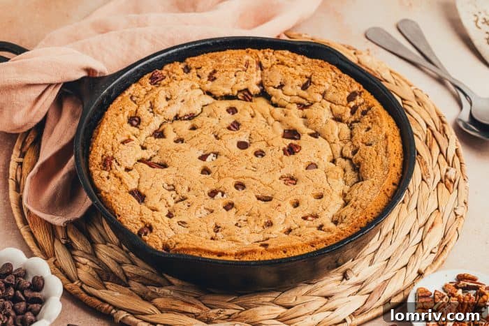 A baked chocolate chip cookie skillet on a placemat with a napkin.