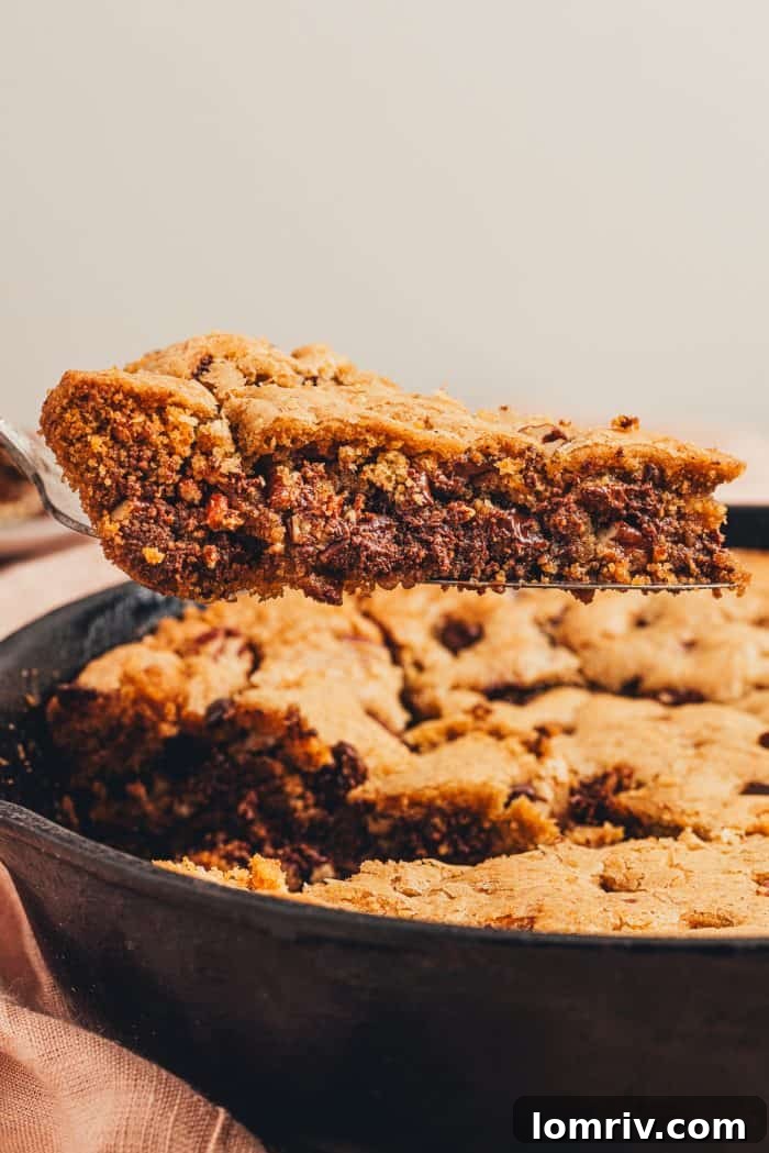A slice of chocolate chip cookie being removed from the skillet.