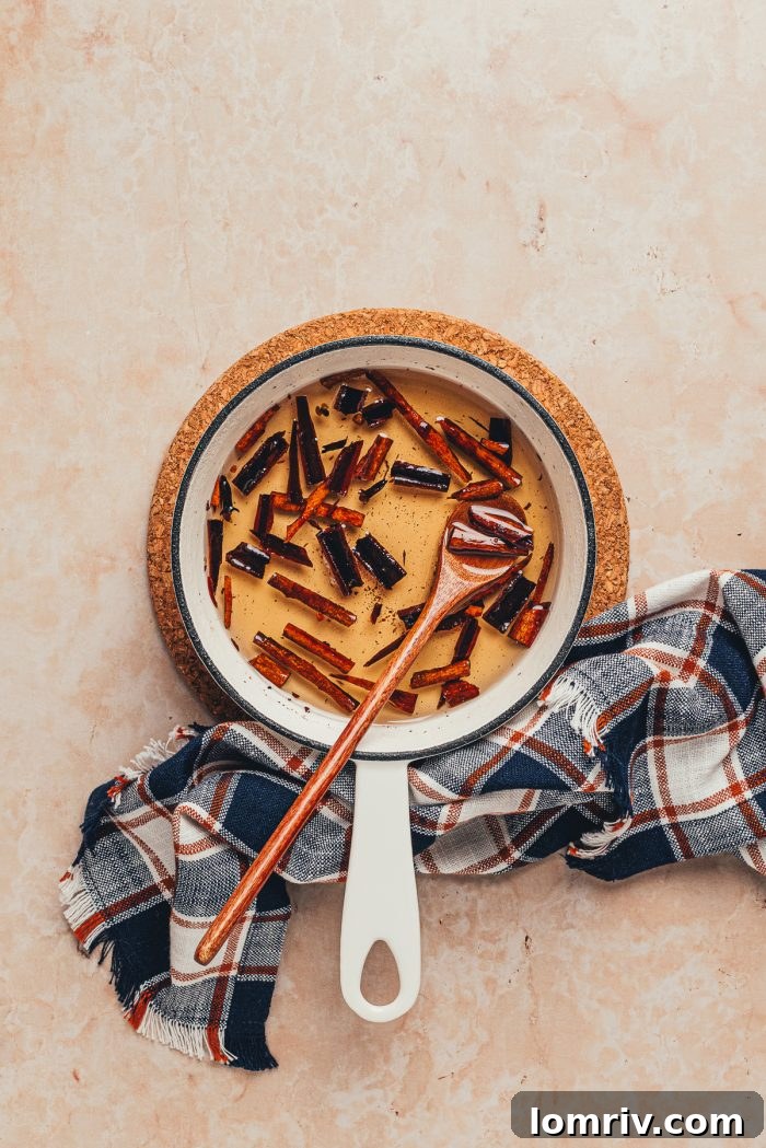 Cinnamon simple syrup in a saucepan with a wooden spoon, after the spices have steeped.