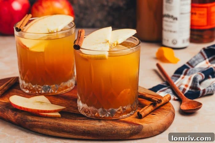 Two glasses of Apple Cider Old Fashioned, garnished with cinnamon sticks and apple slices, perfect for sharing.