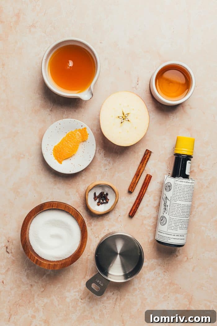 A curated selection of ingredients laid out on a surface, ready for making an Apple Cider Old Fashioned cocktail.