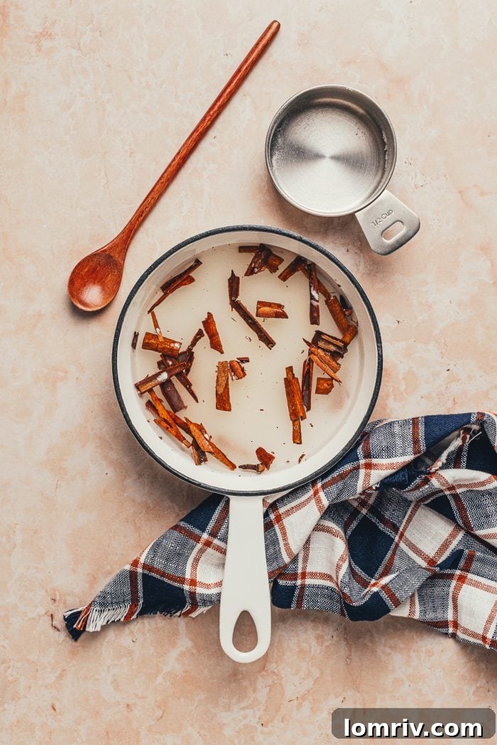 A small saucepan with water and cinnamon sticks, beginning the process of making cinnamon simple syrup.