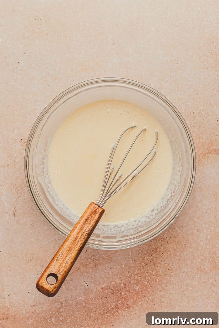 A glass mixing bowl with the cream, egg, and vanilla. 