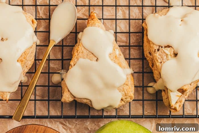 Apple cinnamon scones on a wire rack with a spoon with maple glaze.
