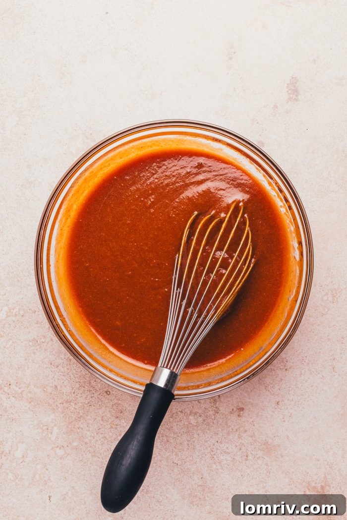A vibrant glass bowl containing pumpkin puree and other liquid ingredients, perfectly blended.