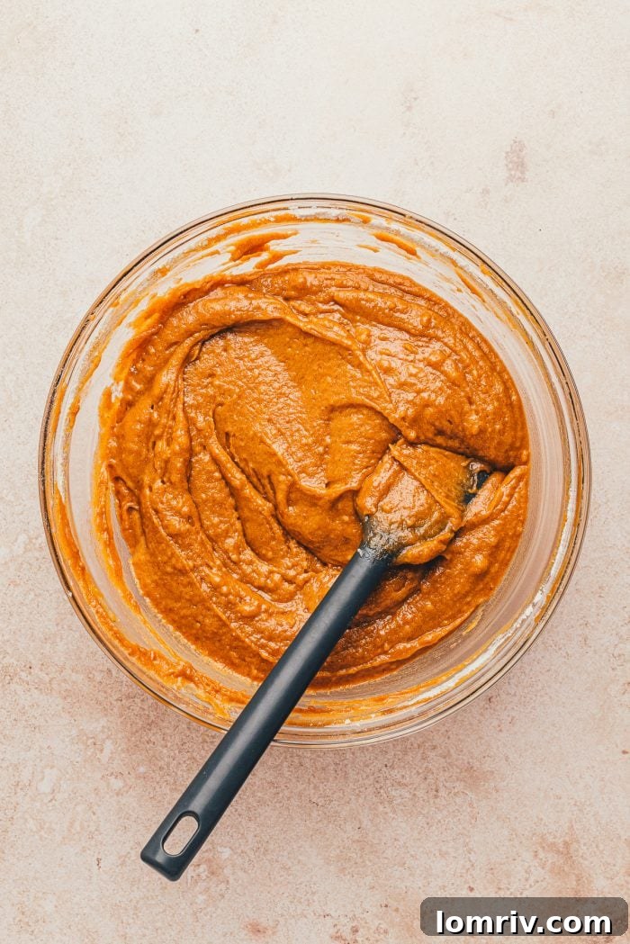 A harmonious blend of wet and dry ingredients in a glass bowl, just combined into a smooth batter.