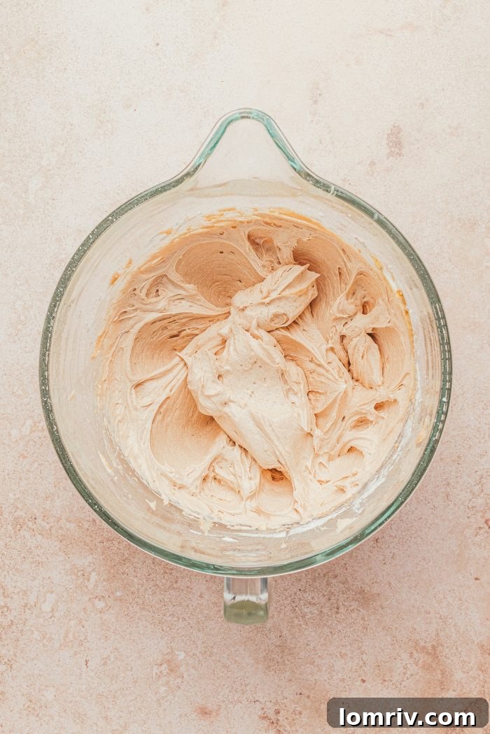 A pristine glass mixing bowl with softened cream cheese and a dash of cinnamon, ready to be whipped into a creamy filling.